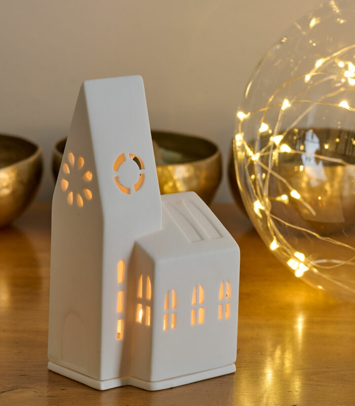 Photophore en porcelaine blanche représentant une église de village. Il diffuse une lumière douce et donne une touche de poésie à votre intérieur. Parfait pour votre décoration des fêtes de fin d’année.